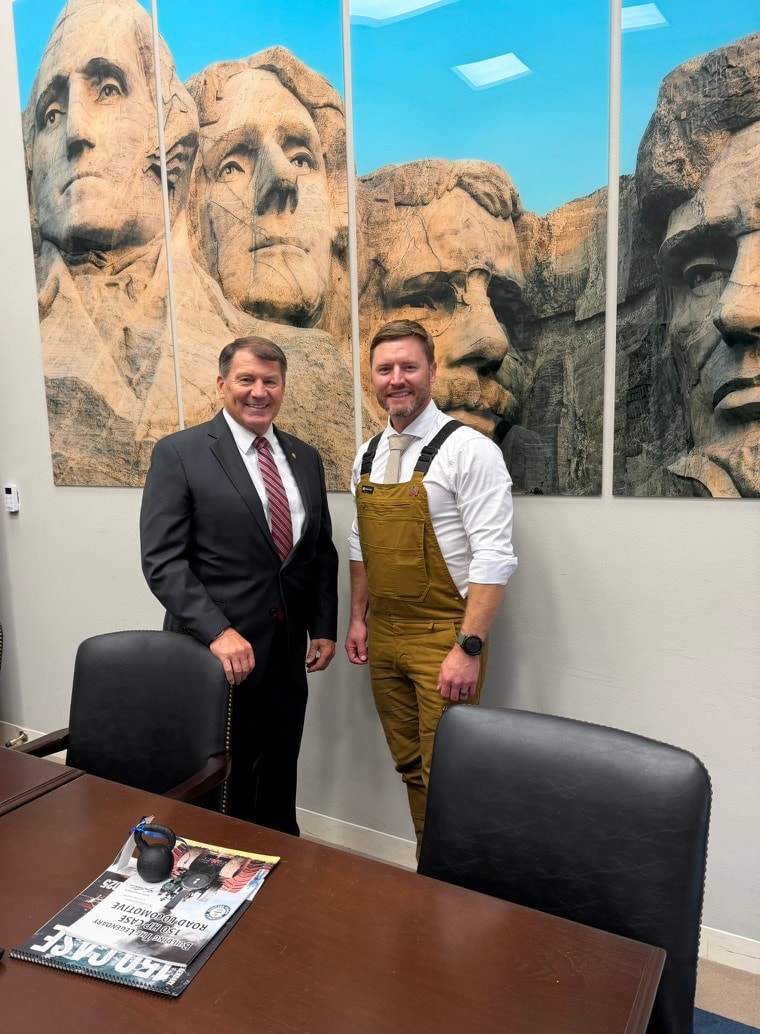 Kory Anderson meeting with a senator, Mount Rushmore artwork in background